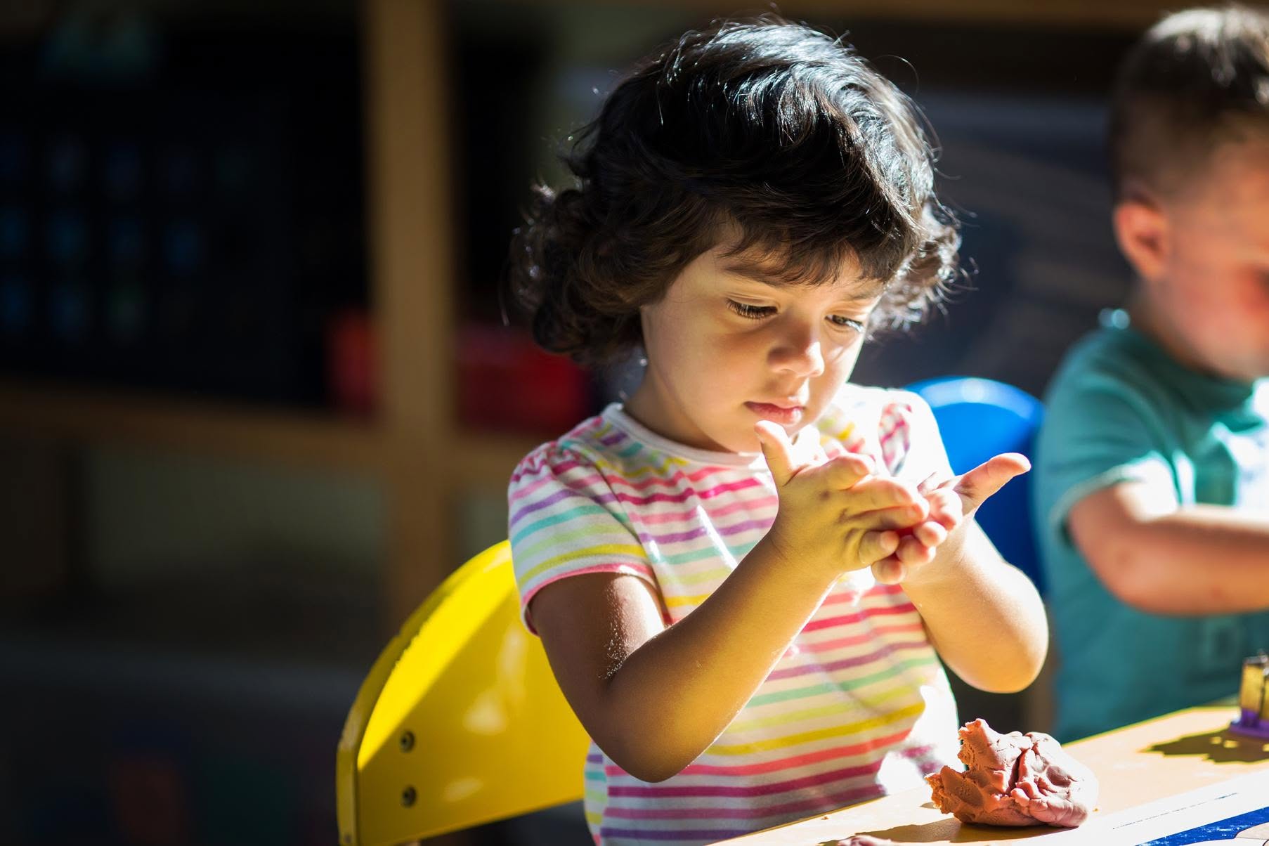 A toddler at our Ramshorn daycare in Laurel shaping playdough in the morning sunlight